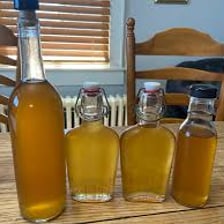 Bottles of homemade spirit beside a small distilling still