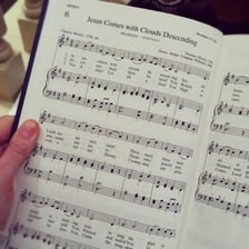 A choir singing from hymn books inside a church