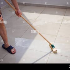 A person vigorously cleaning a tiled floor with a brush