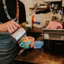 A barista preparing espresso behind a coffee-shop counter