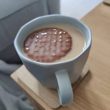 A biscuit being dipped into a cup of tea.
