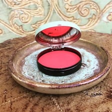 A compact containing red rouge makeup