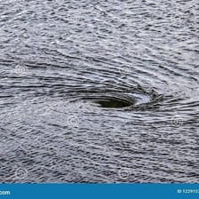 A small circular whirlpool forming in a river.