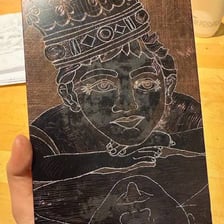 An artist engraving a design on a metal plate.