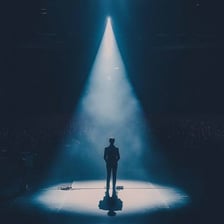 A performer standing under a theatre spotlight