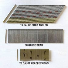 Several small brad nails on a wooden surface.