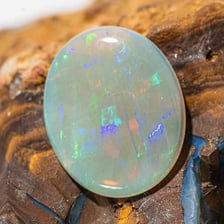 A polished opal gemstone showing iridescent colour
