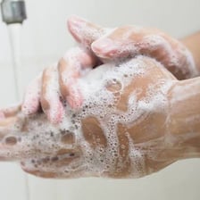 A person cleaning their hands with soap and running water