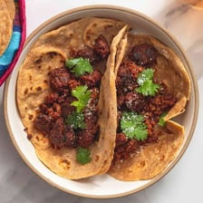 A filled Mexican taco made with a folded tortilla