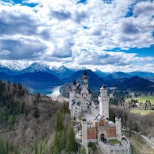 A Bavarian landscape with the Alps and a historic castle.