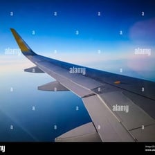 The tip of an airplane wing seen from above the clouds