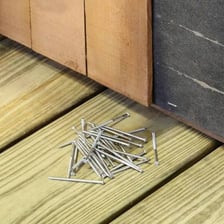 Metal nails lying on a wooden surface.