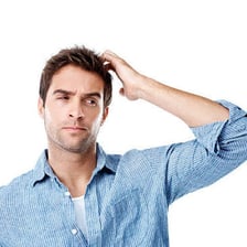 A person touching their head while looking puzzled.