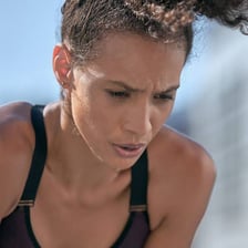 A runner leaning forward and gasping for breath after exertion.