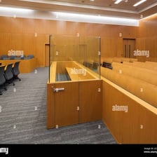 A courtroom view showing a defendant seated in the dock