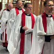 An Anglican vicar wearing clerical robes inside a church