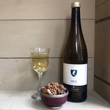 A glass of white Rhine wine beside a vineyard landscape.