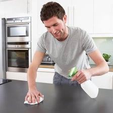 A person wiping dust from a kitchen counter.