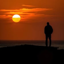 A person casting a long shadow in low evening sunlight.