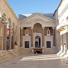 A classical temple surrounded by a row of columns.