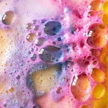 A colorful bath bomb fizzing as it dissolves in bathwater.