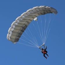 A parachutist using a parachute and associated safety equipment during a jump.