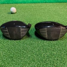 A golf driver positioned beside a golf tee.