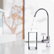 A glass of water beside a running household tap.