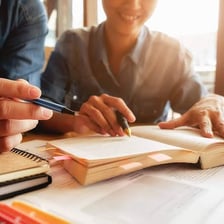 A student studying from a textbook, illustrating the verb “learn.”