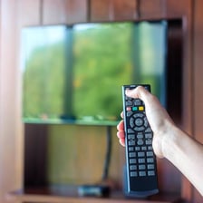 A hand holding a television remote control.