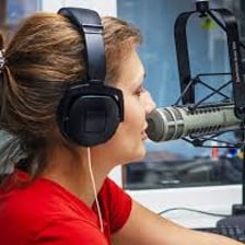 A radio announcer speaking into a studio microphone
