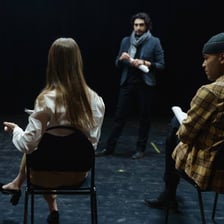 Performers rehearsing a scene on a theatre stage.