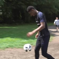 A football player repeatedly tapping a ball into the air.