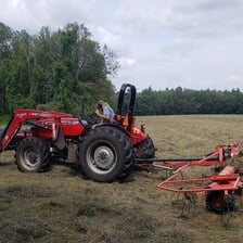 Farm machinery working in a field during haymaking.