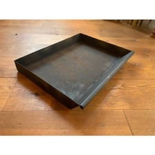 A metal ash pan used beneath a fireplace