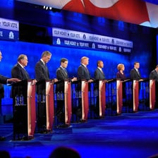 Several candidates standing on a debate stage.