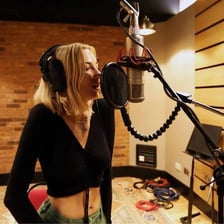 A singer performing into a microphone in a recording studio.