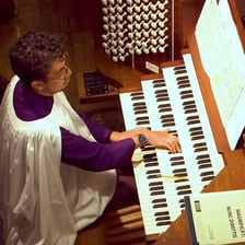 An organist playing the keyboard of a pipe organ.