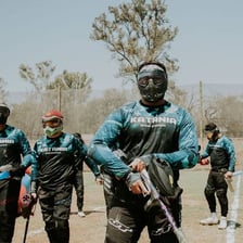 Paintball players in protective masks playing outdoors
