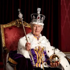 A royal crown displayed on a throne.