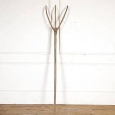A traditional wooden pitchfork with several tines.