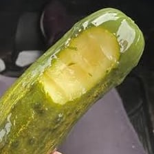 A person making a disgusted expression after tasting a pickle.