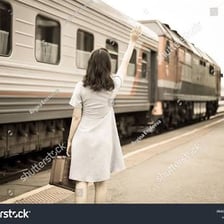A person leaving a railway station with luggage
