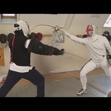 Two fencers making an attacking move with their swords.