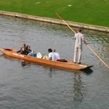 A traditional punt boat being steered on a river