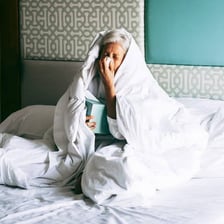 A person resting in bed while recovering from a cold