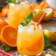 A glass of orangeade garnished with orange slices