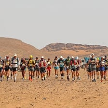 Runners taking part in a marathon across a dry desert landscape.
