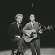 Simon and Garfunkel performing together on stage.