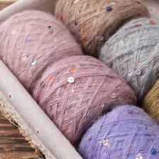 Hands using knitting needles to make a knitted fabric.